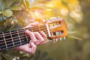 close up hand of woman playing acoustic guitar.