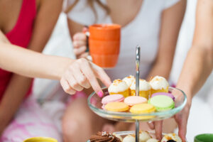 friends or teen girls eating sweets at home